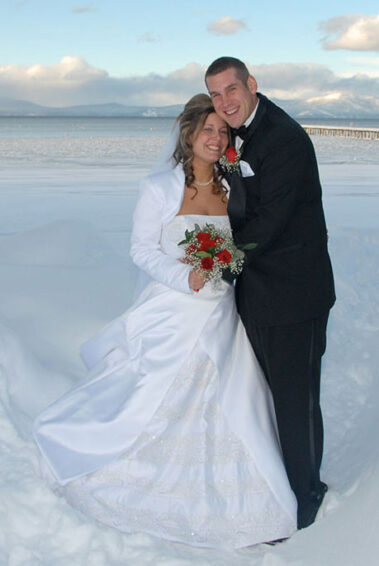 A man and woman in wedding attire standing on the beach.