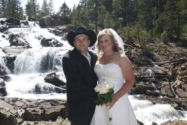 A man and woman posing for a picture in front of a waterfall.