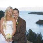 A man and woman posing for a picture on the side of a lake.