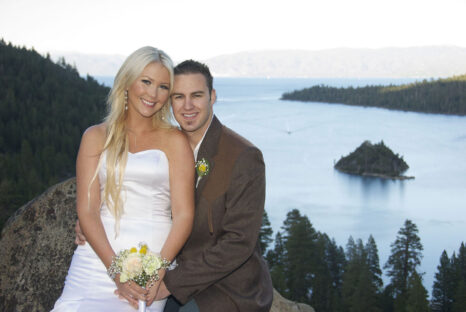 A man and woman posing for a picture on the side of a lake.