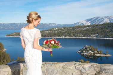 A bride holding her bouquet of flowers near the water.