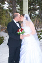 A bride and groom kissing in the snow.