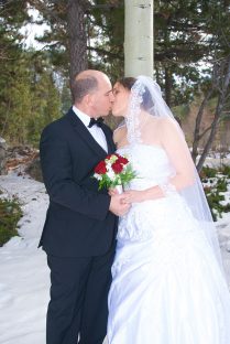 A bride and groom kissing in the snow.