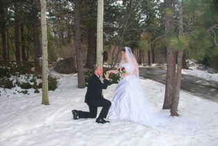 A man kneeling down to propose to his bride.
