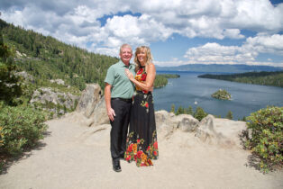 A man and woman posing for a picture on top of a mountain.