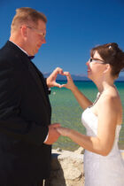 A man and woman holding hands on the beach.