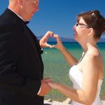 A man and woman holding hands on the beach.