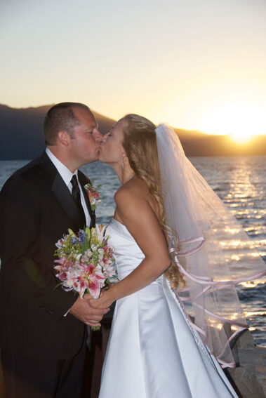 A bride and groom kissing on the beach