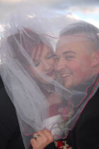 A man and woman under the veil of their wedding dress.