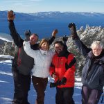 A group of people standing on top of a snow covered slope.