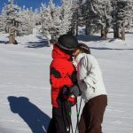 Two people kissing on a ski slope.