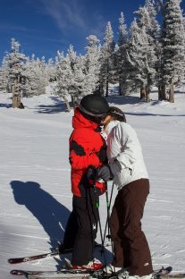 Two people kissing on a ski slope.