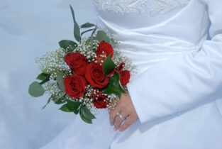A bride holding her bouquet of roses and greenery.