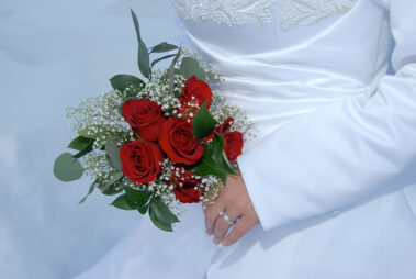A bride holding her bouquet of roses and greenery.