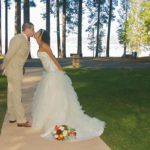 A bride and groom kissing on the side of a walkway.