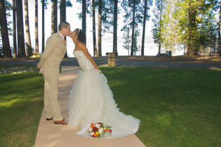 A bride and groom kissing on the side of a walkway.