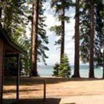 A cabin with trees and water in the background.